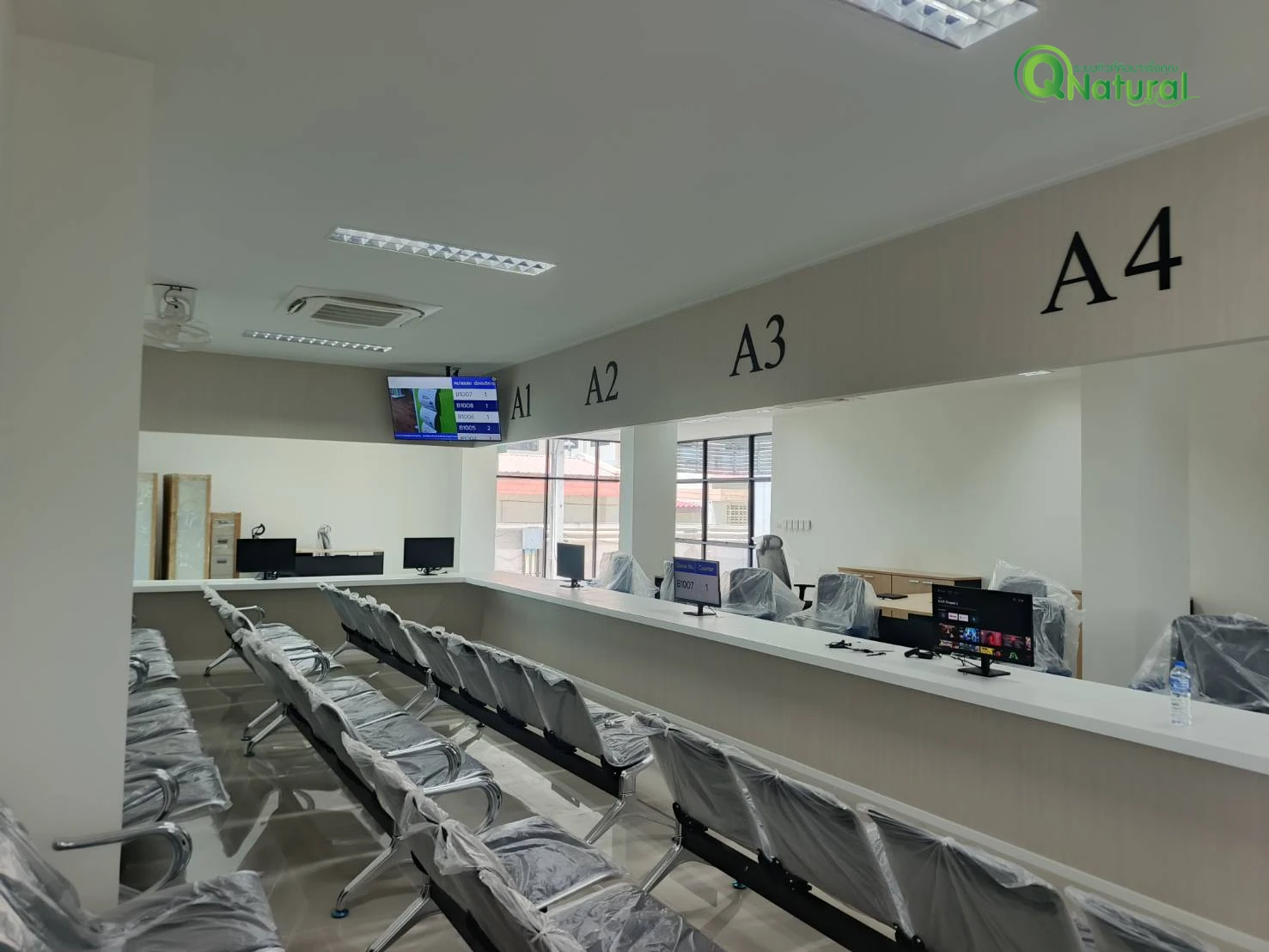 ห้องโถงบริการที่สำนักงานตรวจคนเข้าเมืองสมุทรสาคร มีช่องบริการ A1 ถึง A4 ที่นั่งรอจำนวนมาก และจอแสดงผลคิวติดผนัง