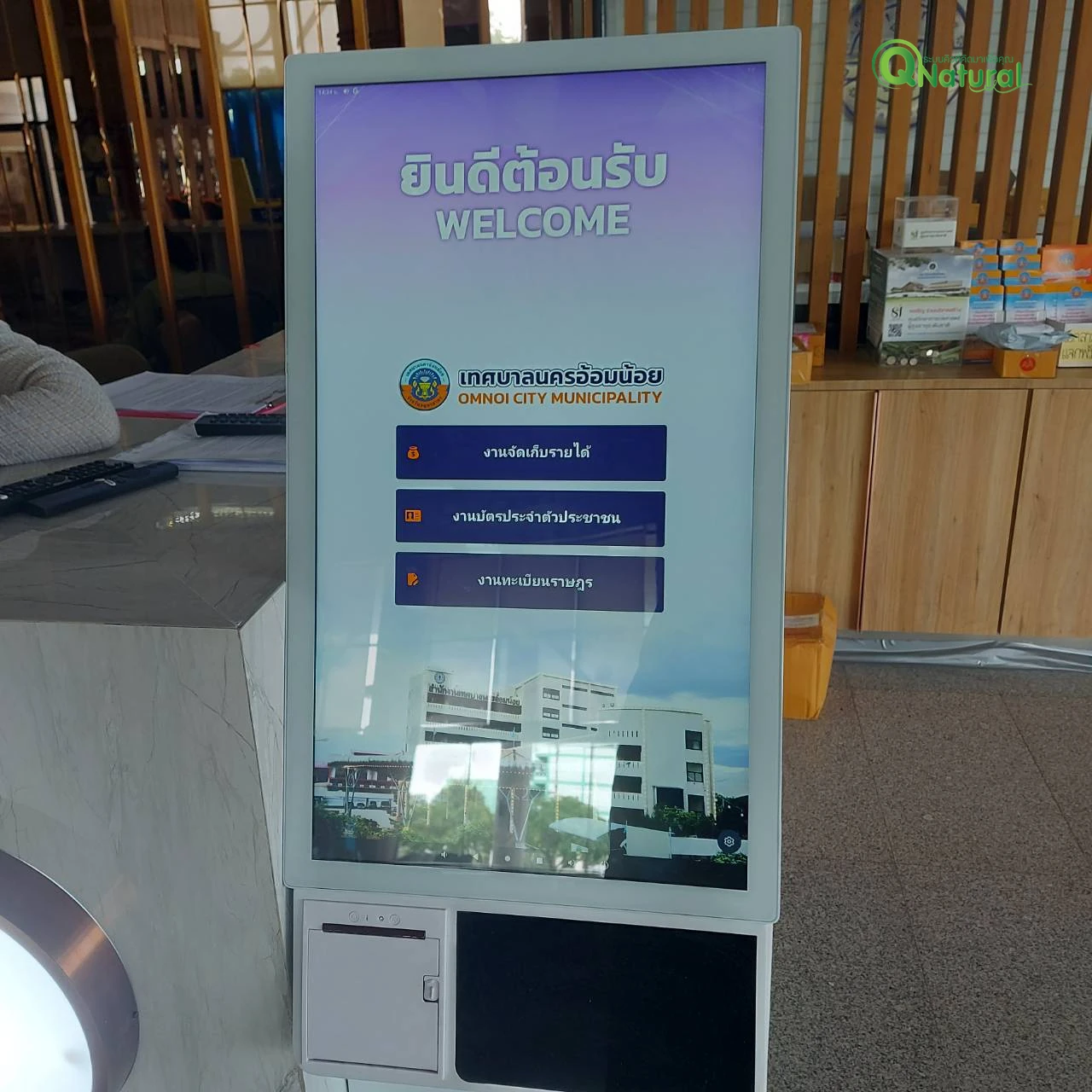 ตู้กดบัตรคิวหน้าจอสัมผัสตั้งพื้นที่เทศบาลนครอ้อมน้อย แสดงหน้าจอยินดีต้อนรับและปุ่มเลือกบริการ