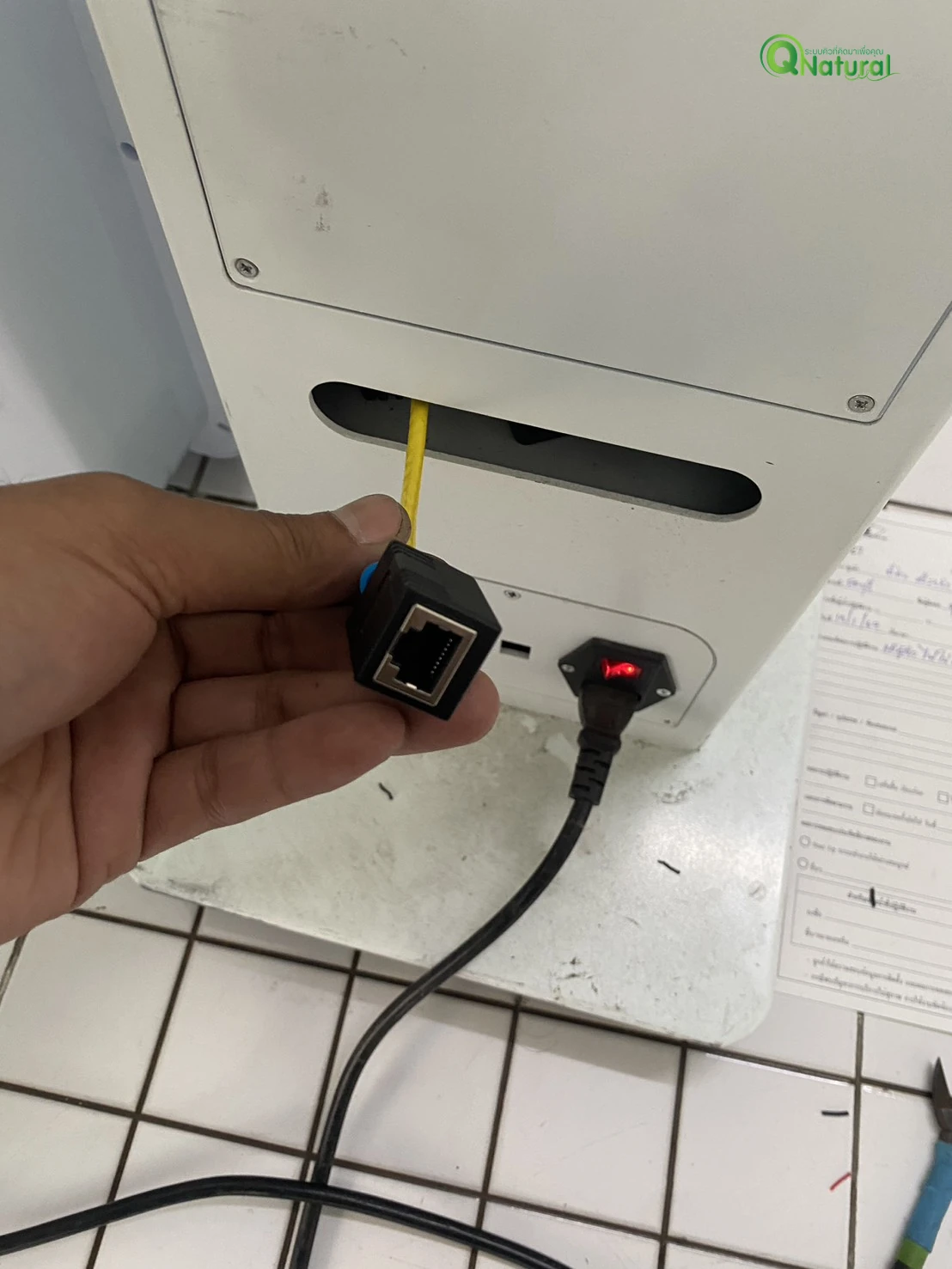 ช่างเซอร์วิสตรวจหัวต่อ RJ45 และสาย LAN สีเหลืองที่ด้านหลังเครื่องกดบัตรคิว สำนักงานที่ดินสาขาศรีราชา