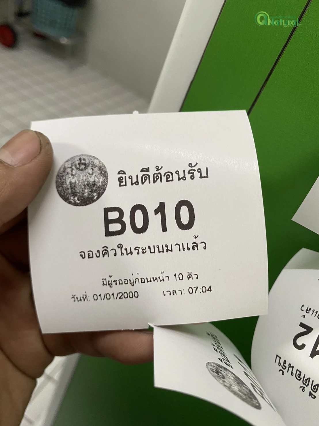 บัตรคิวทดสอบหมายเลข B010 จากเครื่องกดบัตรคิวที่สำนักงานที่ดินจังหวัดชลบุรี สาขาศรีราชา พร้อมตราครุฑ