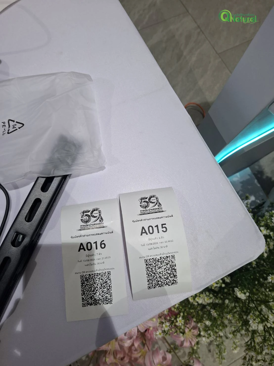 บัตรคิวที่พิมพ์จากระบบ ระบุหมายเลขคิว จำนวนผู้รอ เวลาโดยประมาณ และ QR Code สำหรับตรวจสอบคิว